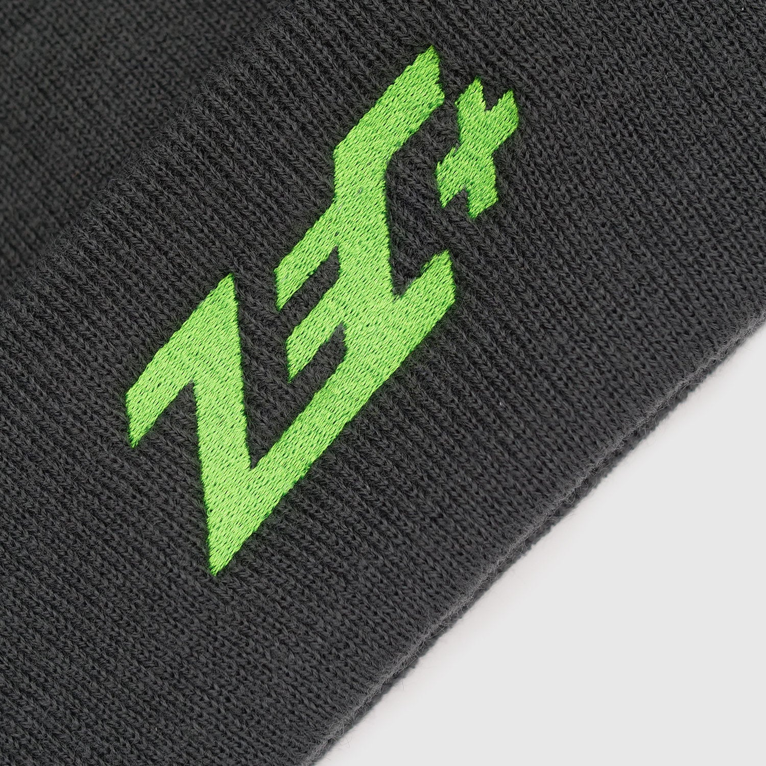 Detailansicht der grünen Logo-Stickerei auf grauer Strickmütze