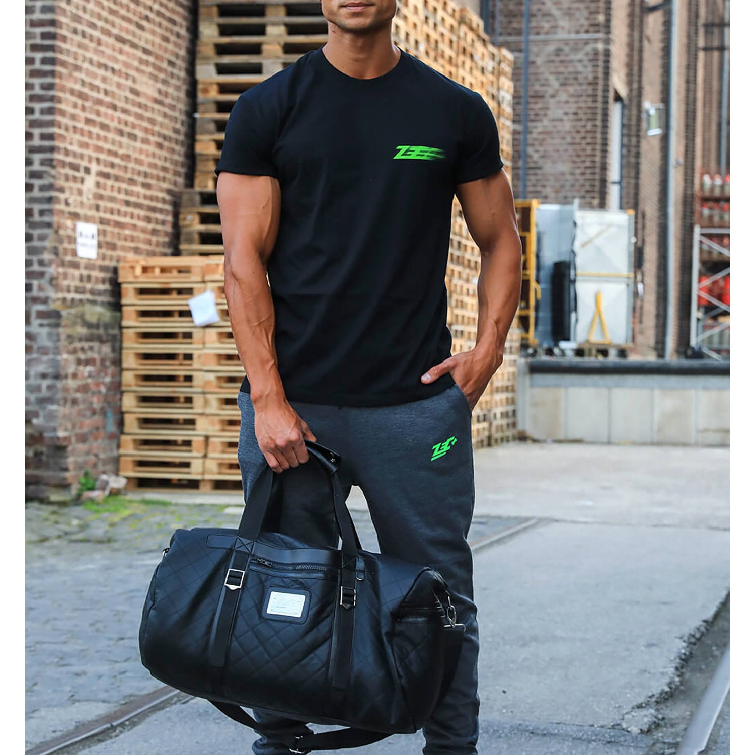 Zecplus Lifestyle Weekender Tasche Sporttasche schwarz gesteppt getragen von Mann vor Paletten