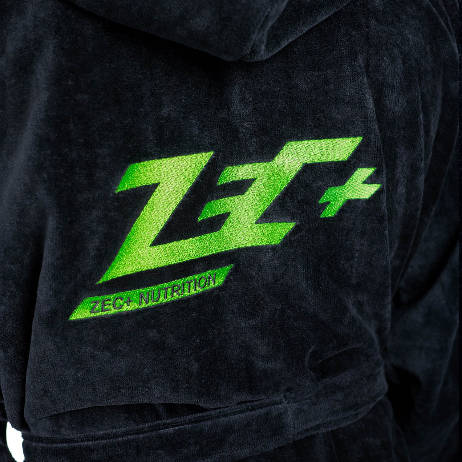Nahaufnahme des grün gestickten Zec+ Logos auf schwarzem Bademantel